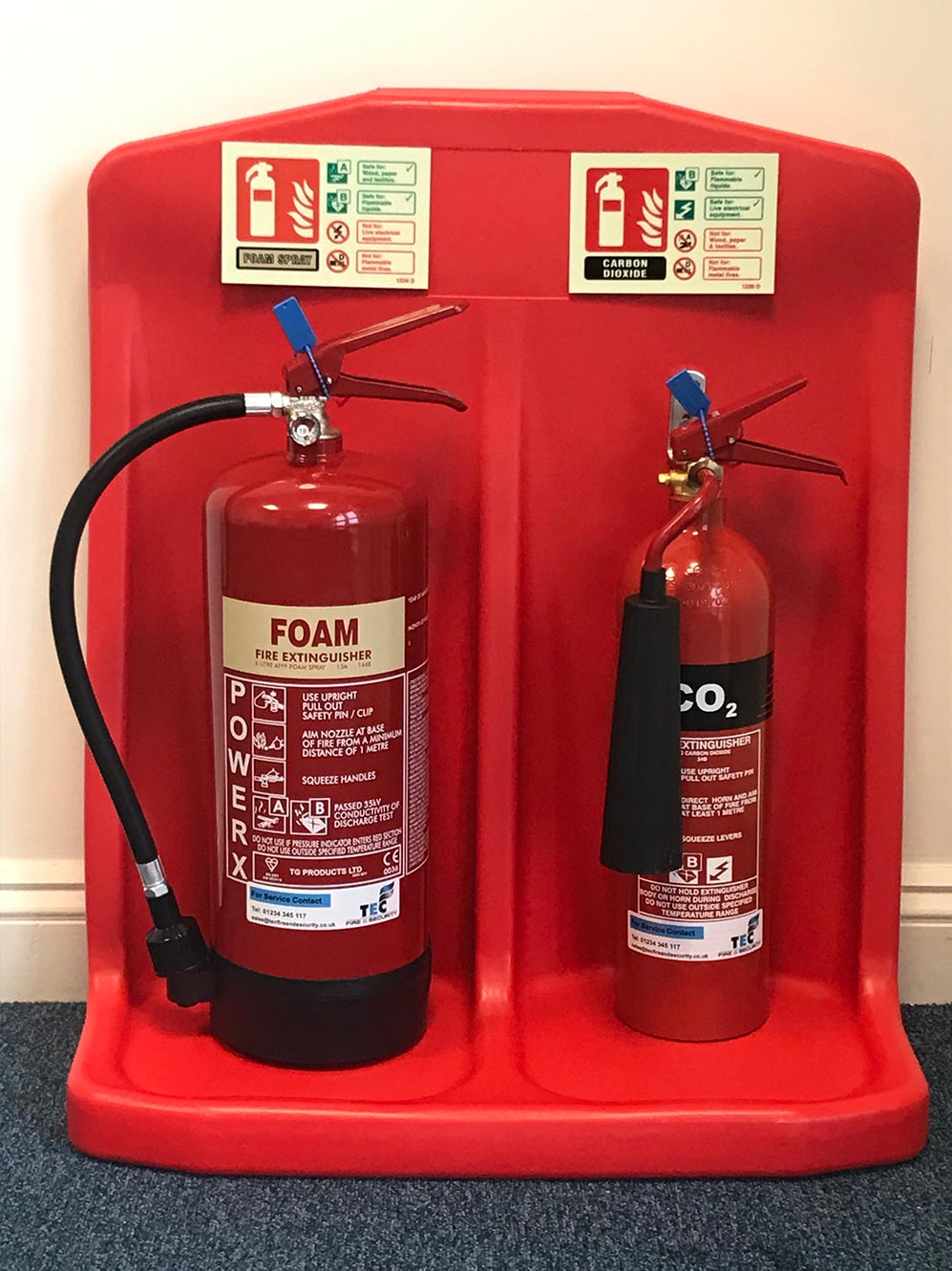 Foam and CO2 fire extinguishers on stand with signage